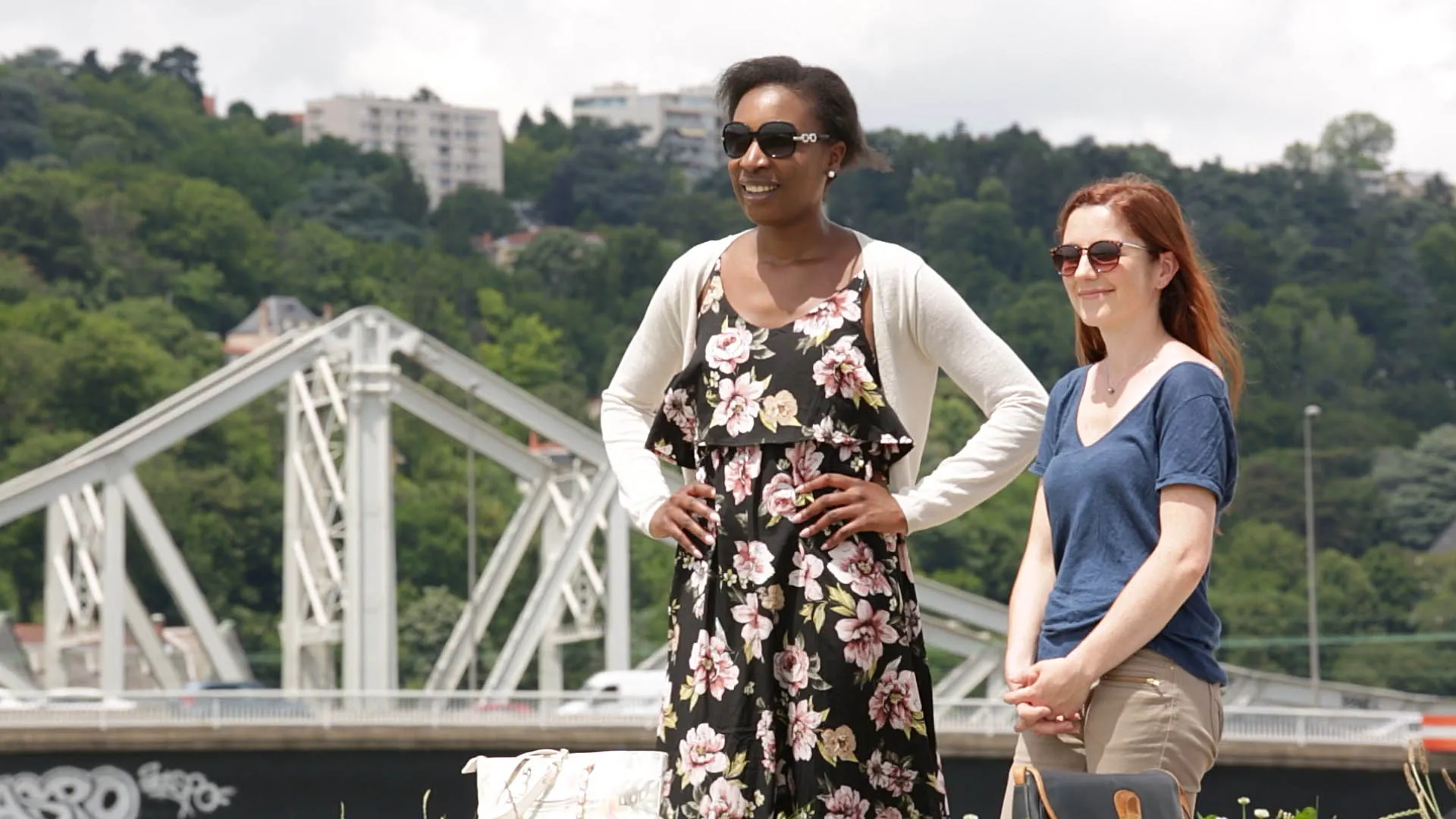 Two French actors stand in front of a bridge
