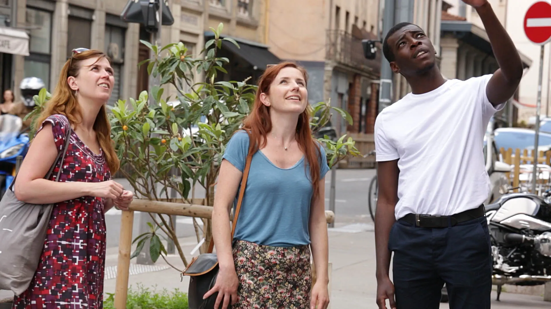 Three French actors look off screen at a mural